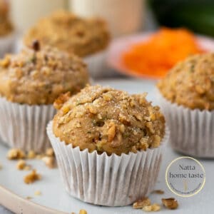 muffins de zucchini y zanahoria con nueces alrededor servidos en un plato redondo