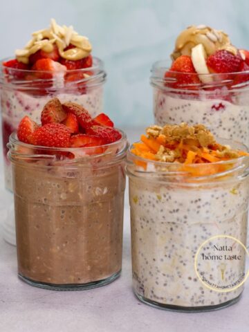 Vasos de vidrio con avena trasnochada decorada con fresas, mantequilla de maní, zanahoria rallada y otros toppings, ideal para un desayuno saludable y meal prep.