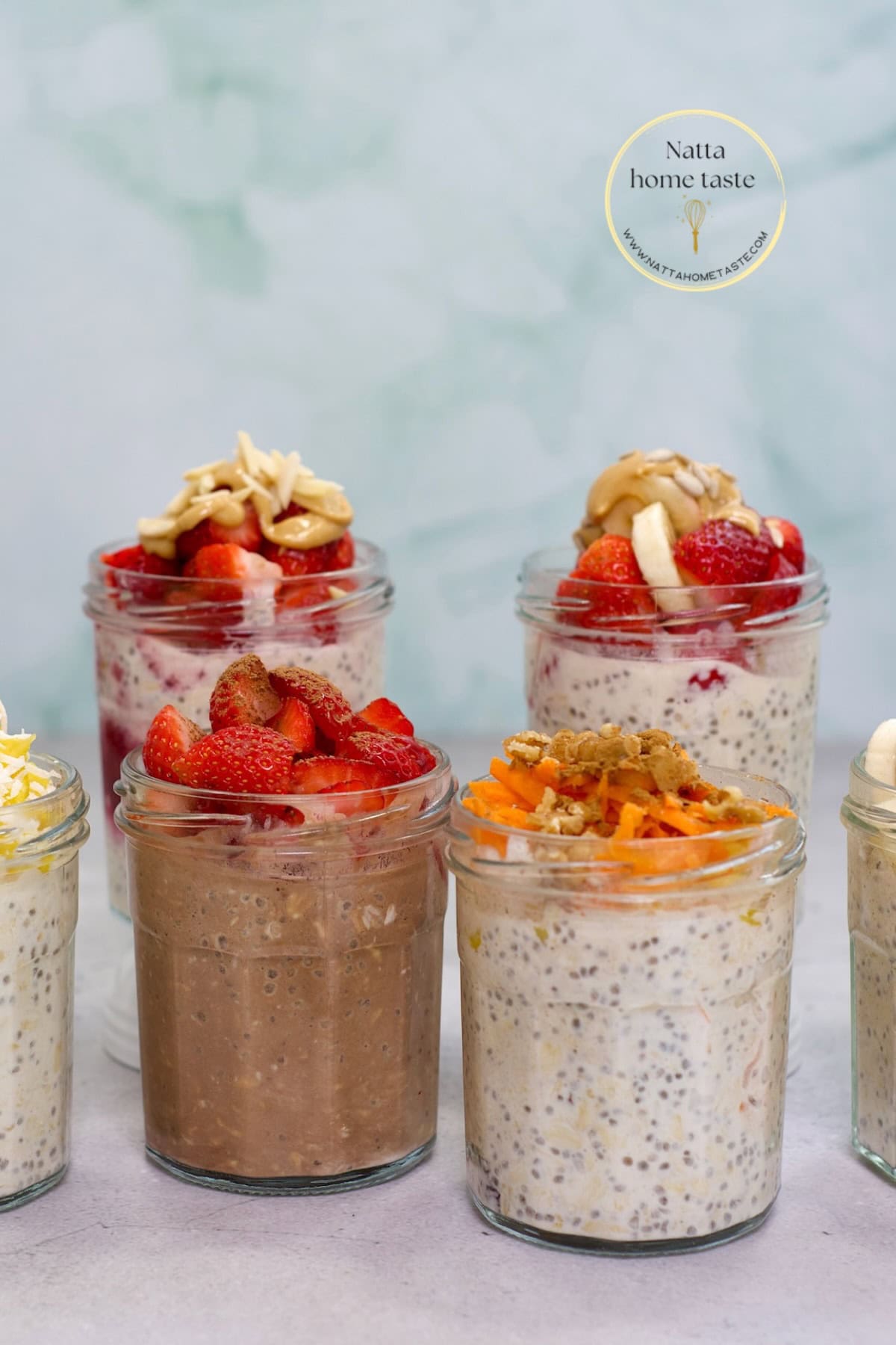 Vasos de vidrio con avena trasnochada decorada con fresas, mantequilla de maní, zanahoria rallada y otros toppings, ideal para un desayuno saludable y meal prep.