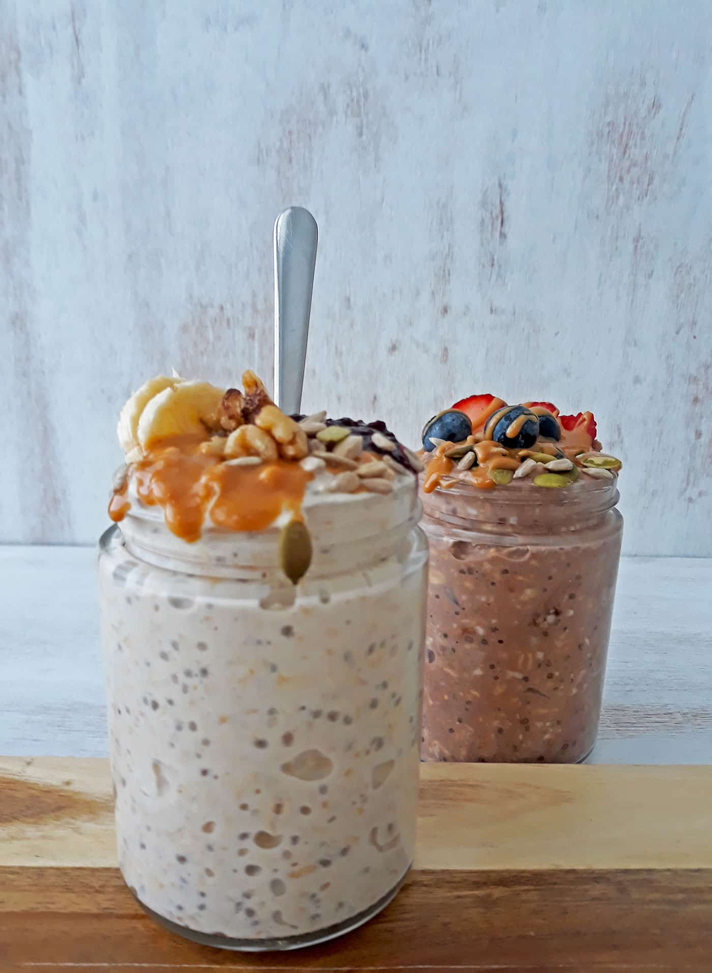 mason jars con avena remojada y una cuchara sobre una tabla de madera