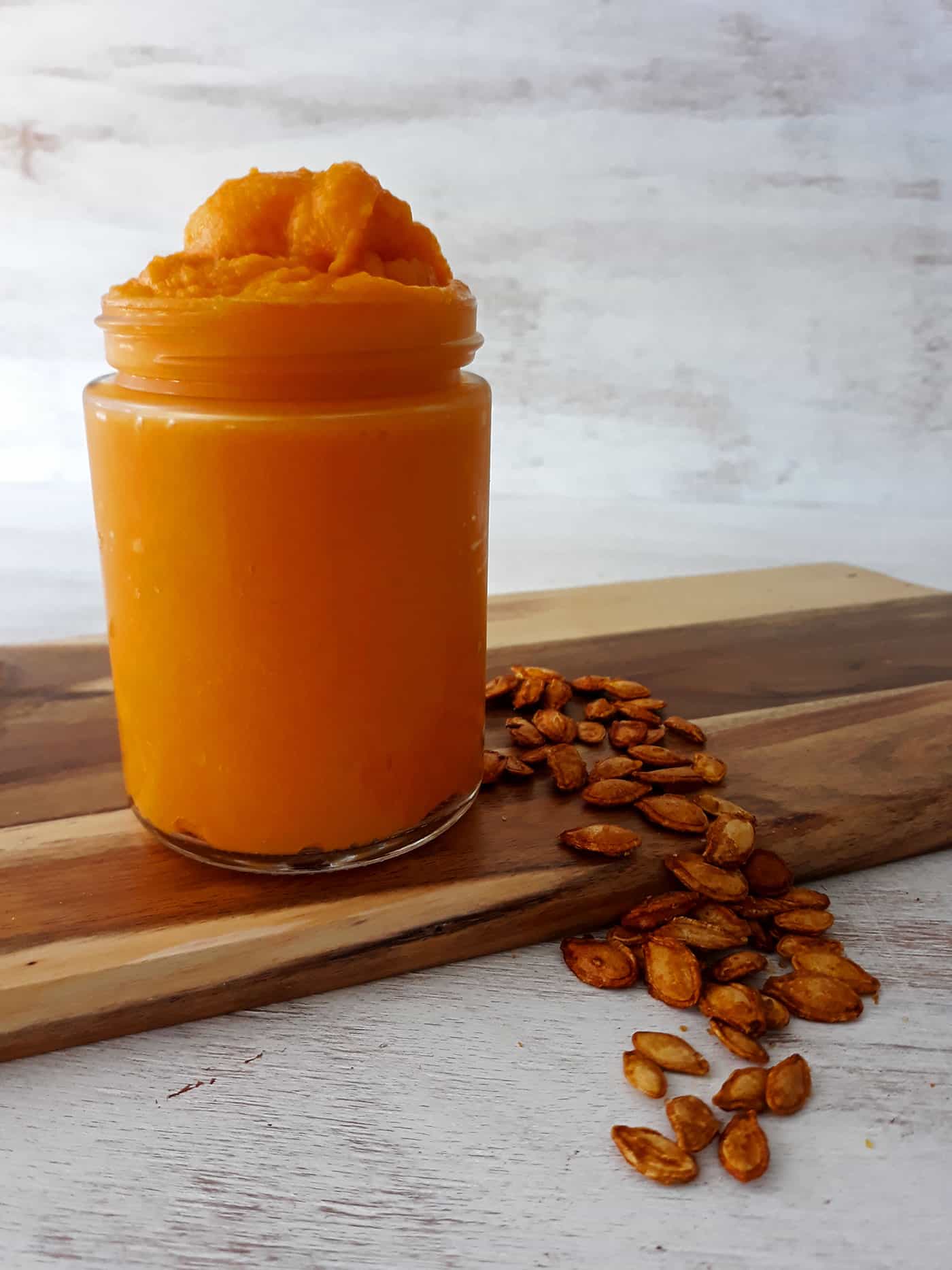 puré de calabaza en contenedor de vidrio acompañado de pepitas