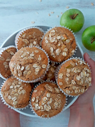 muffins de manzana en un contenedor blanco con dos manzanas frescas