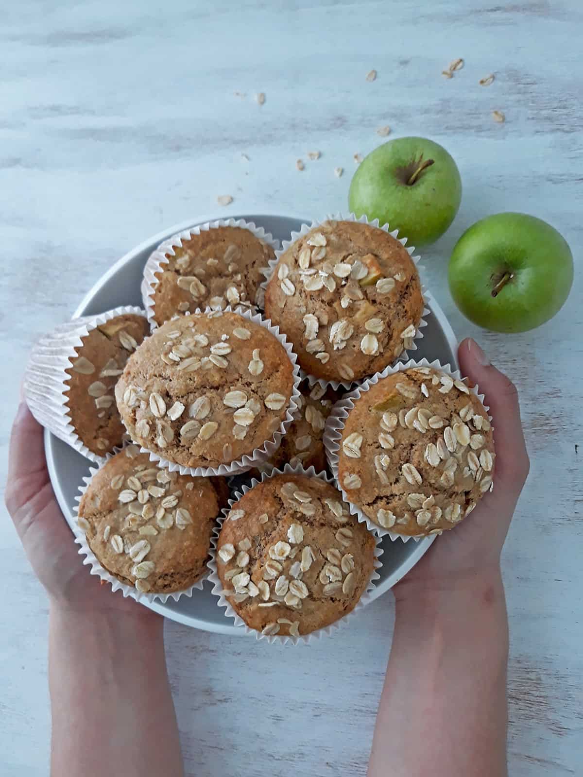 muffins de manzana en un contenedor blanco con dos manzanas frescas