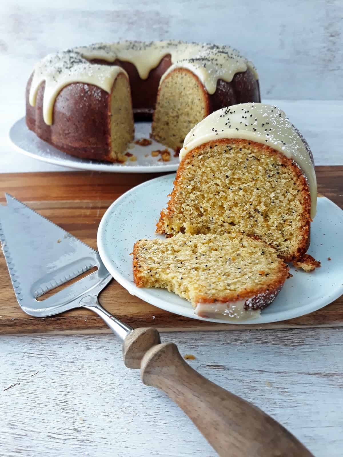 porción de torta de naranja servida en un plato redondo, con la torta entera en el fondo