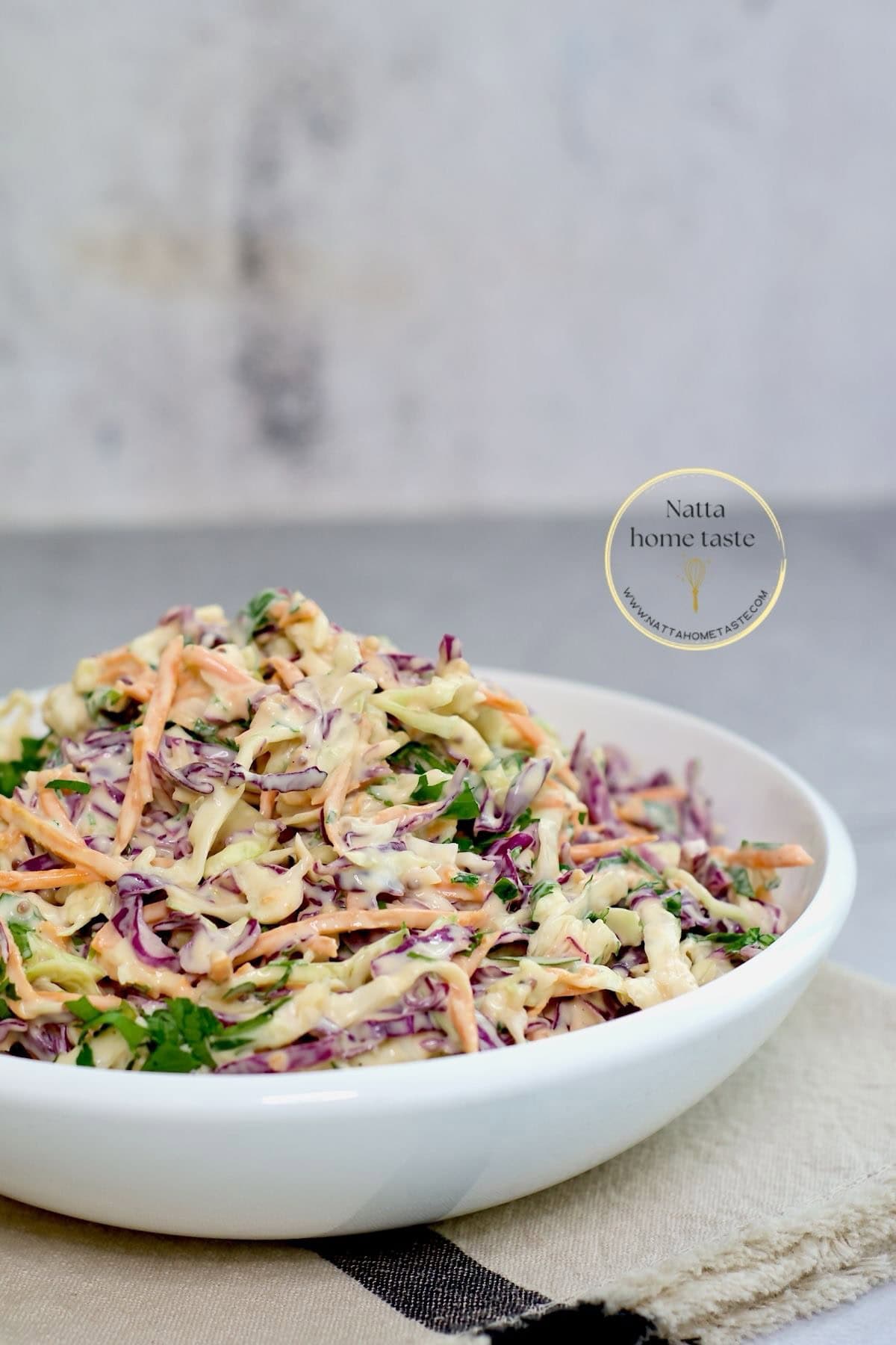 ensalada de repollo y zanahoria con mayonesa en un bol blanco sobre una mesa