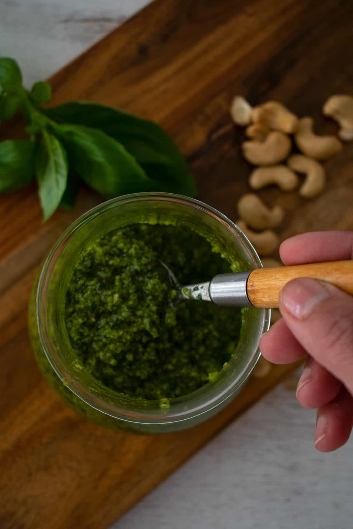 sirviendo salsa pesto con cuchara de madera