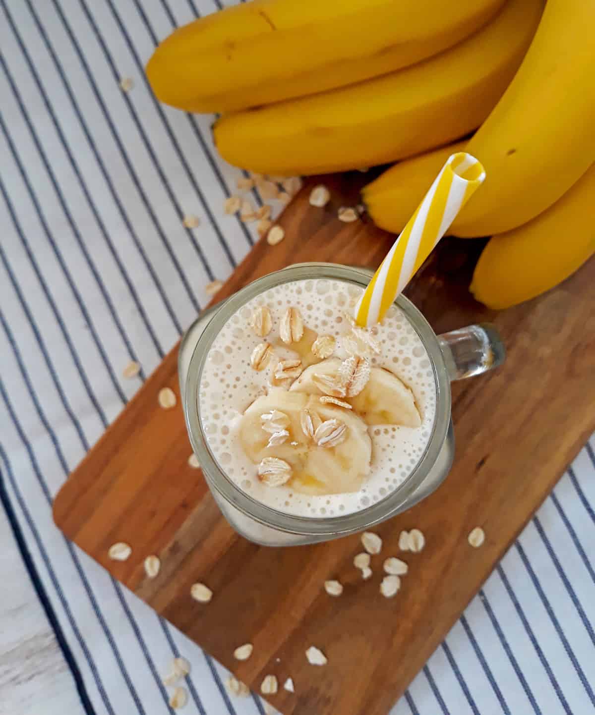 smoothie de banana con un pitillo amarillo y blanco y bananas frescas