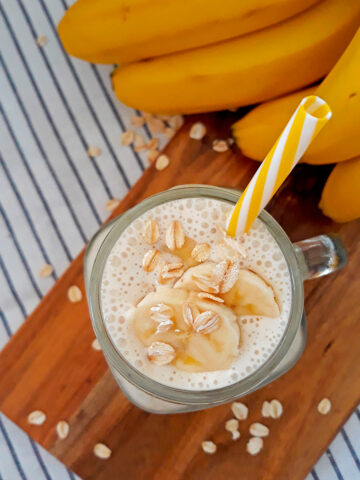 smoothie de banana con un pitillo amarillo y blanco acompañado de bananas