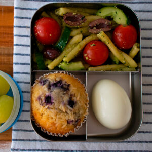 lonchera con ensalada de pasta, muffin, huevo duro y uvas