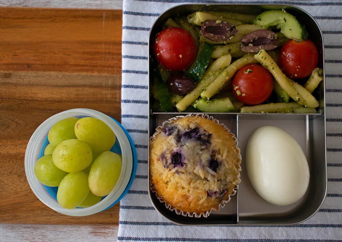 lonchera con ensalada de pasta pesto, muffin y uvas