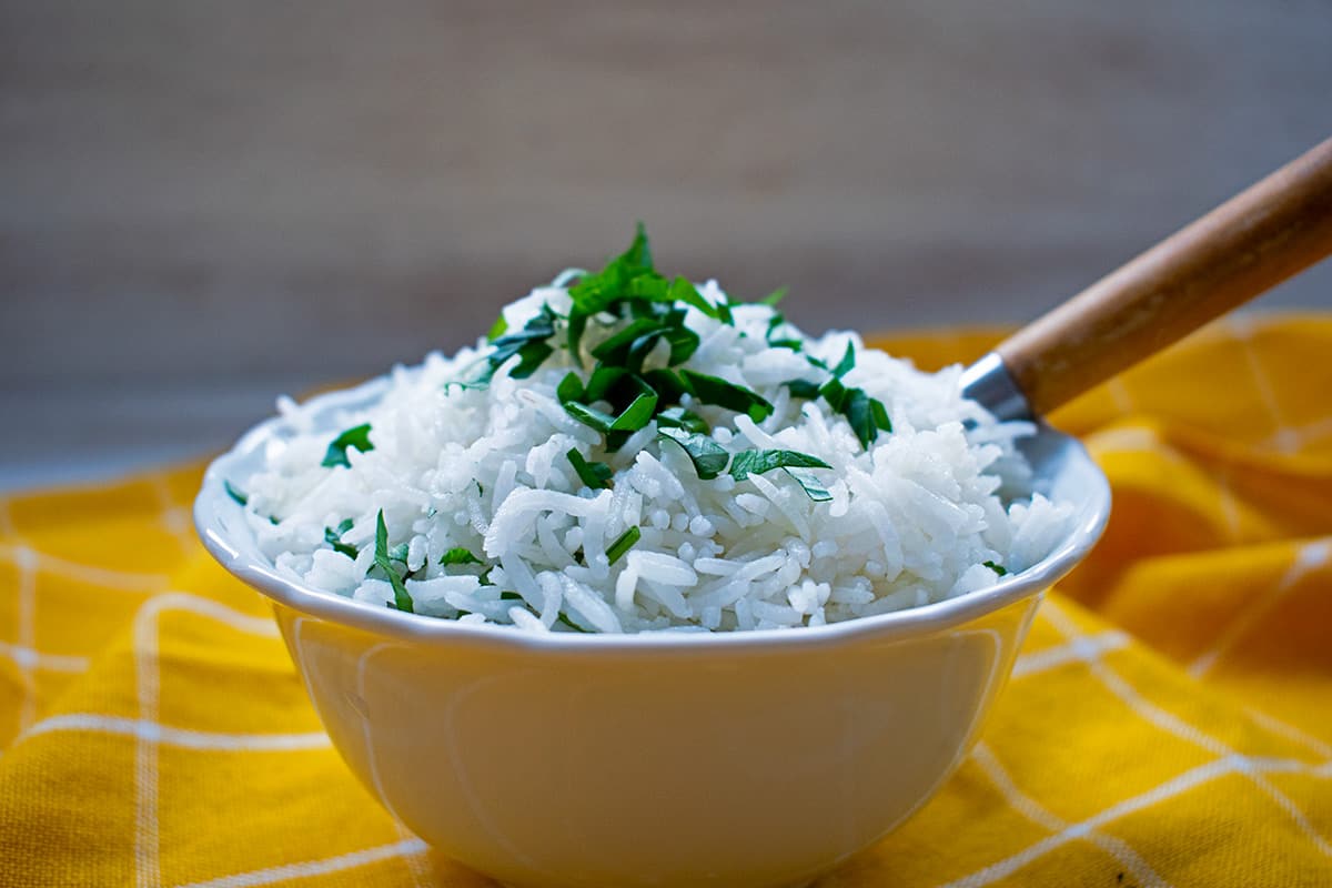 arroz blanco en un bol blanco con una cuchara de madera