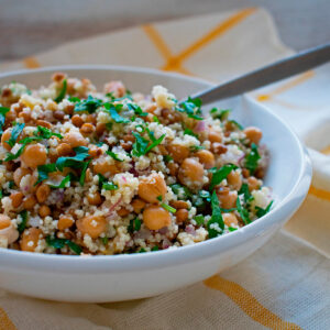 ensalada de cuscus y garbanzos servida en un bol blanco