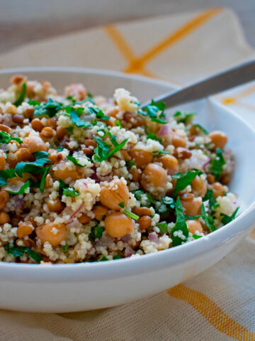 ensalada de cuscus y garbanzos servida en un bol blanco