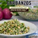 Ensalada de garbanzos mediterránea en un recipiente redondo blanco sobre una mesa con un tenedor.