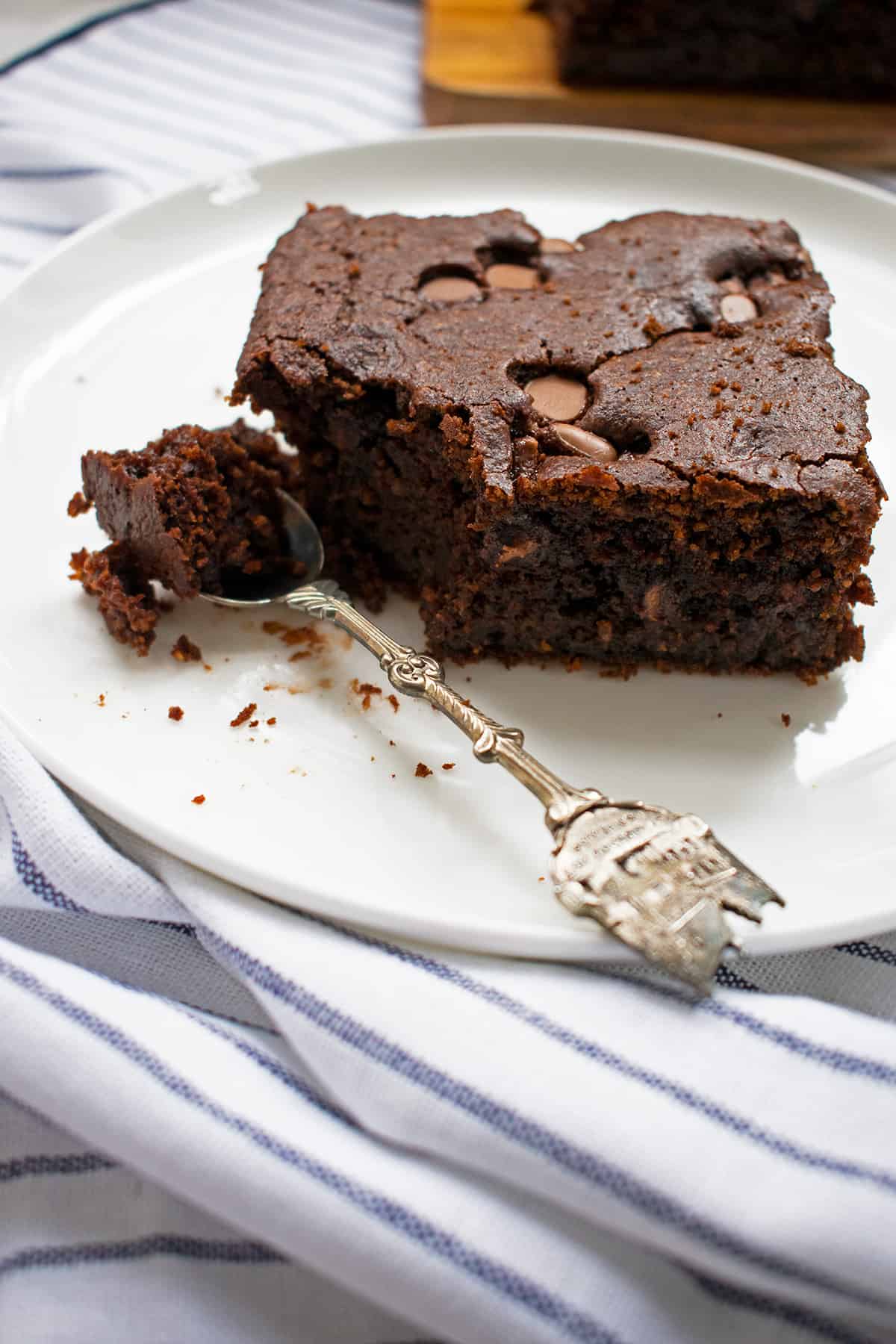 brownie de chocolate servido en un plato blanco con una cuchara pequeña