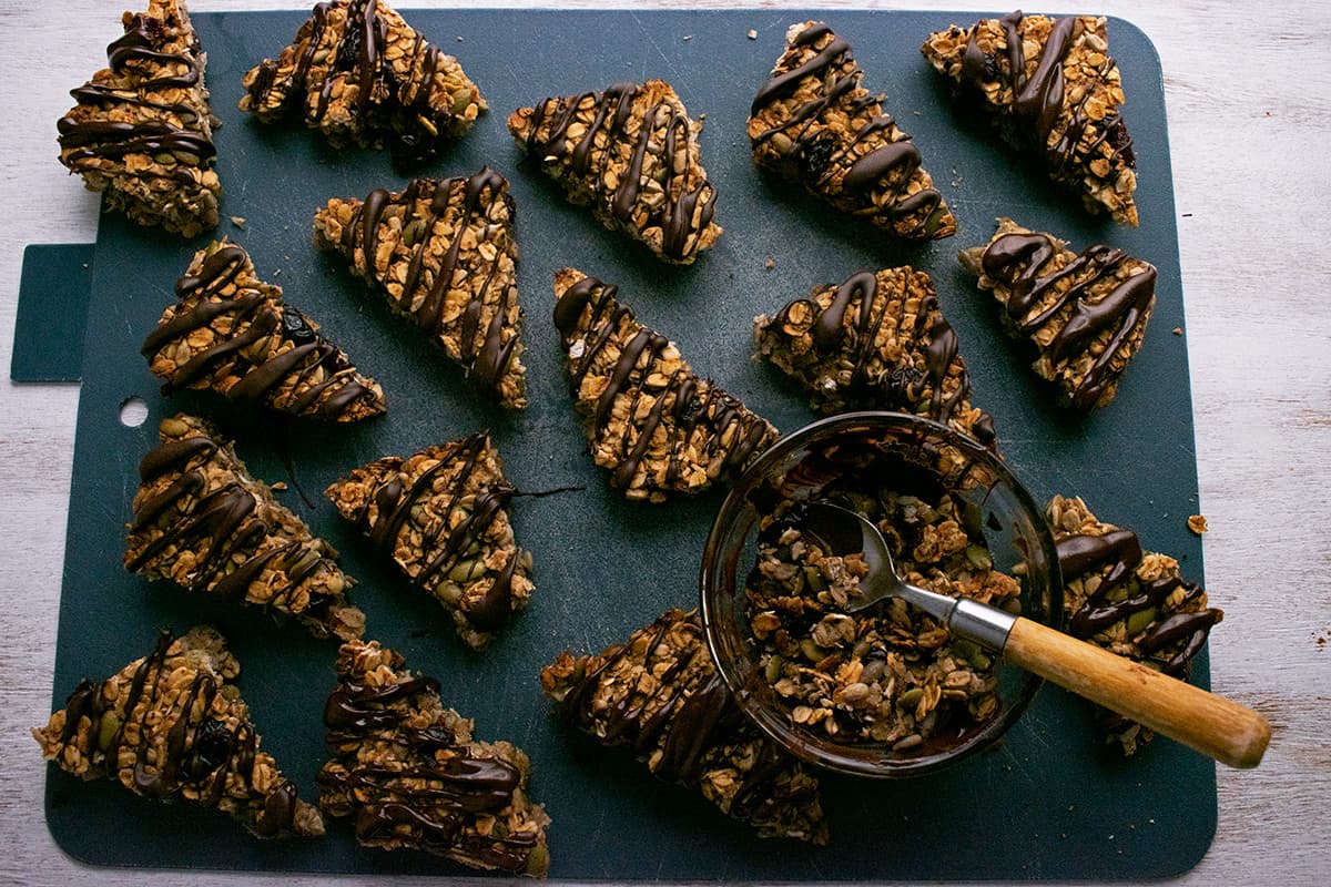 barritas de avena con chocolate derretido por encima sobre una tabla para cortar.