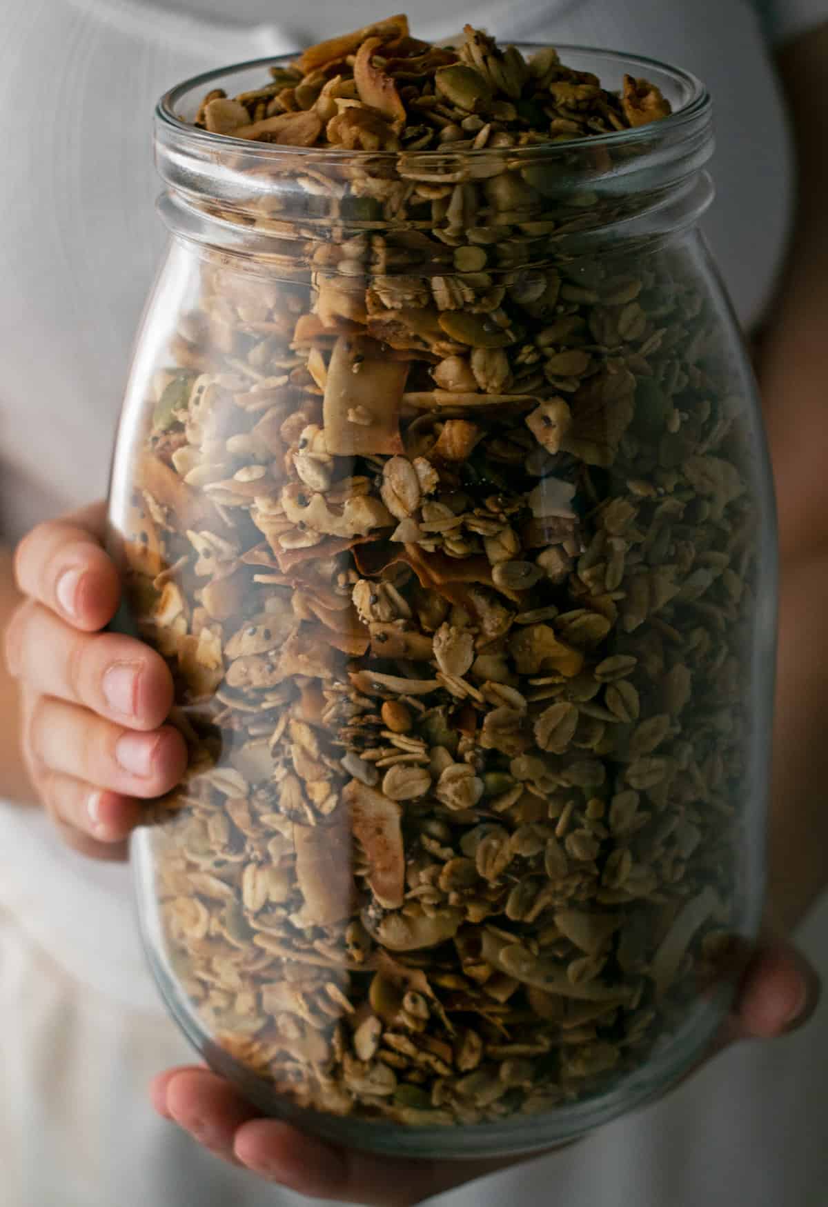 granola en un frasco de vidrio sostenido por las manos de una mujer