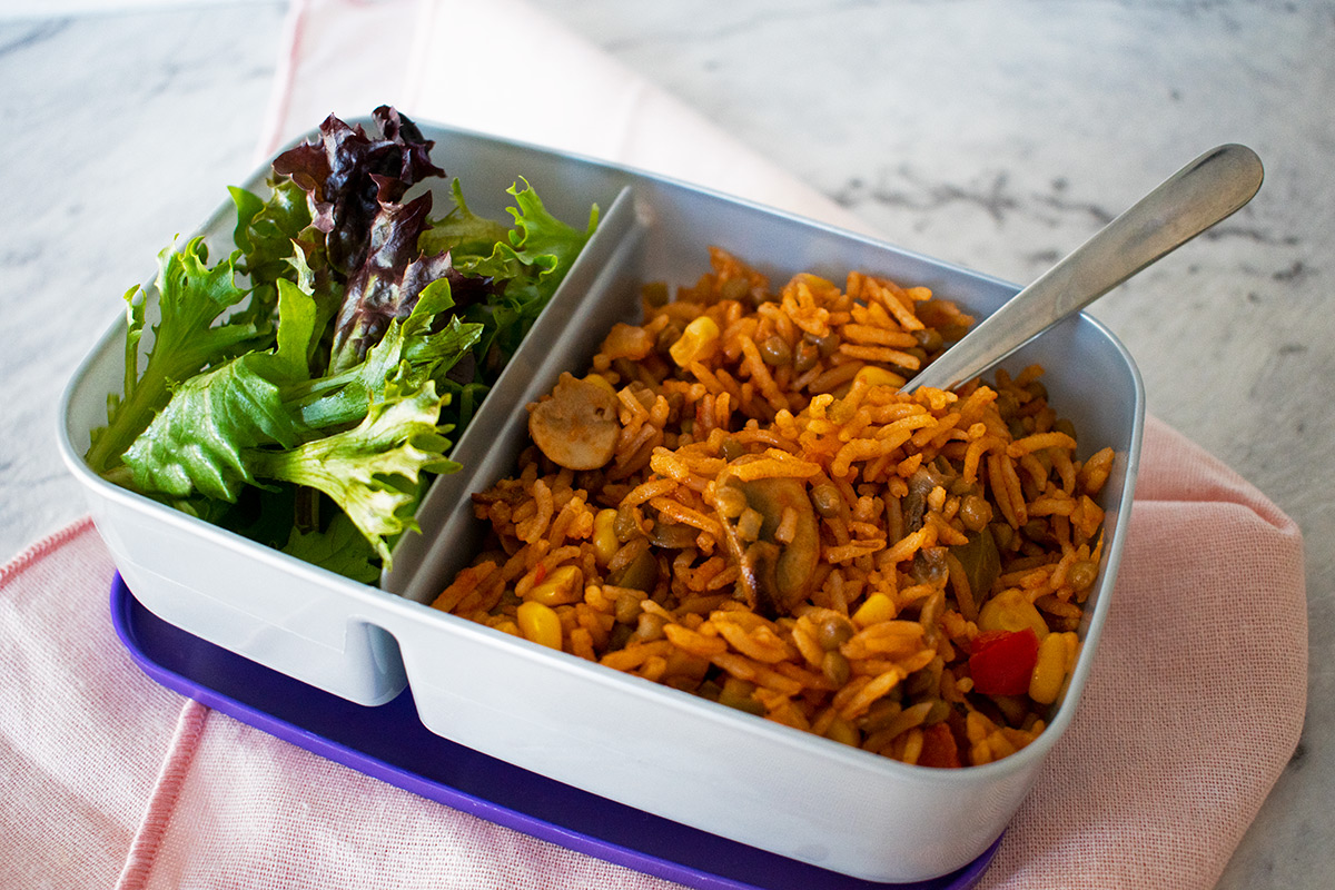 arroz con verduras en una lonchera plastica acompañado de ensalada.