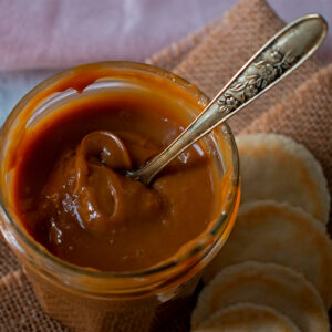 Frasco de vidrio con dulce de leche acompañado de pequeñas galletas redondas