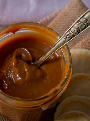 Frasco de vidrio con dulce de leche acompañado de pequeñas galletas redondas