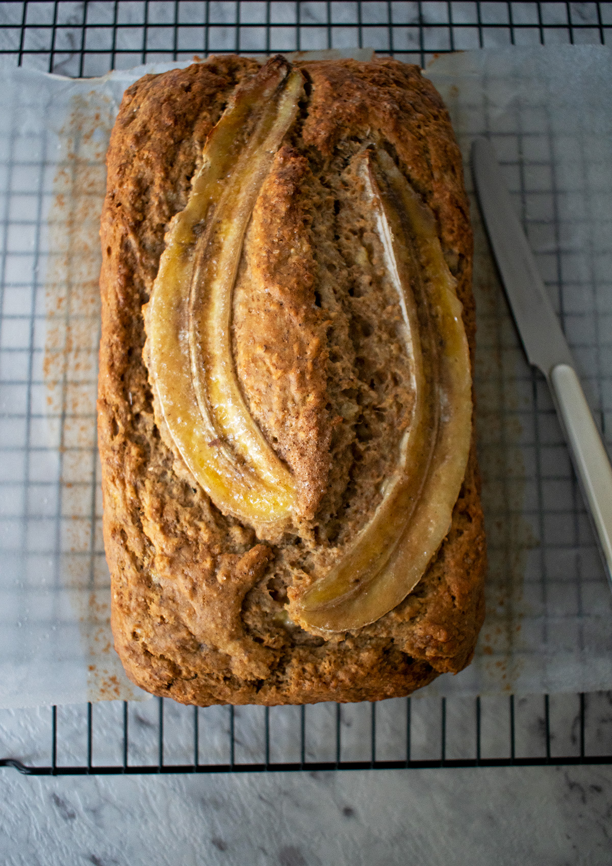 Pan de banana sobre una rejilla con un cuchillo al lado.