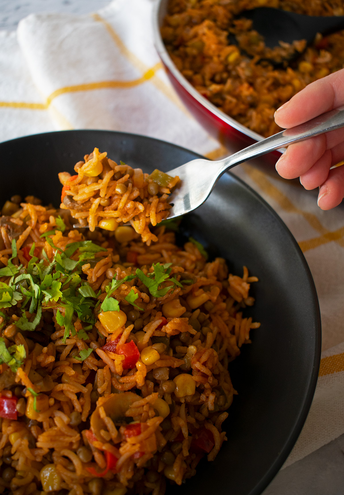 arroz pilaf servido en un plato negro sobre un paño blanco con lineas amarillas