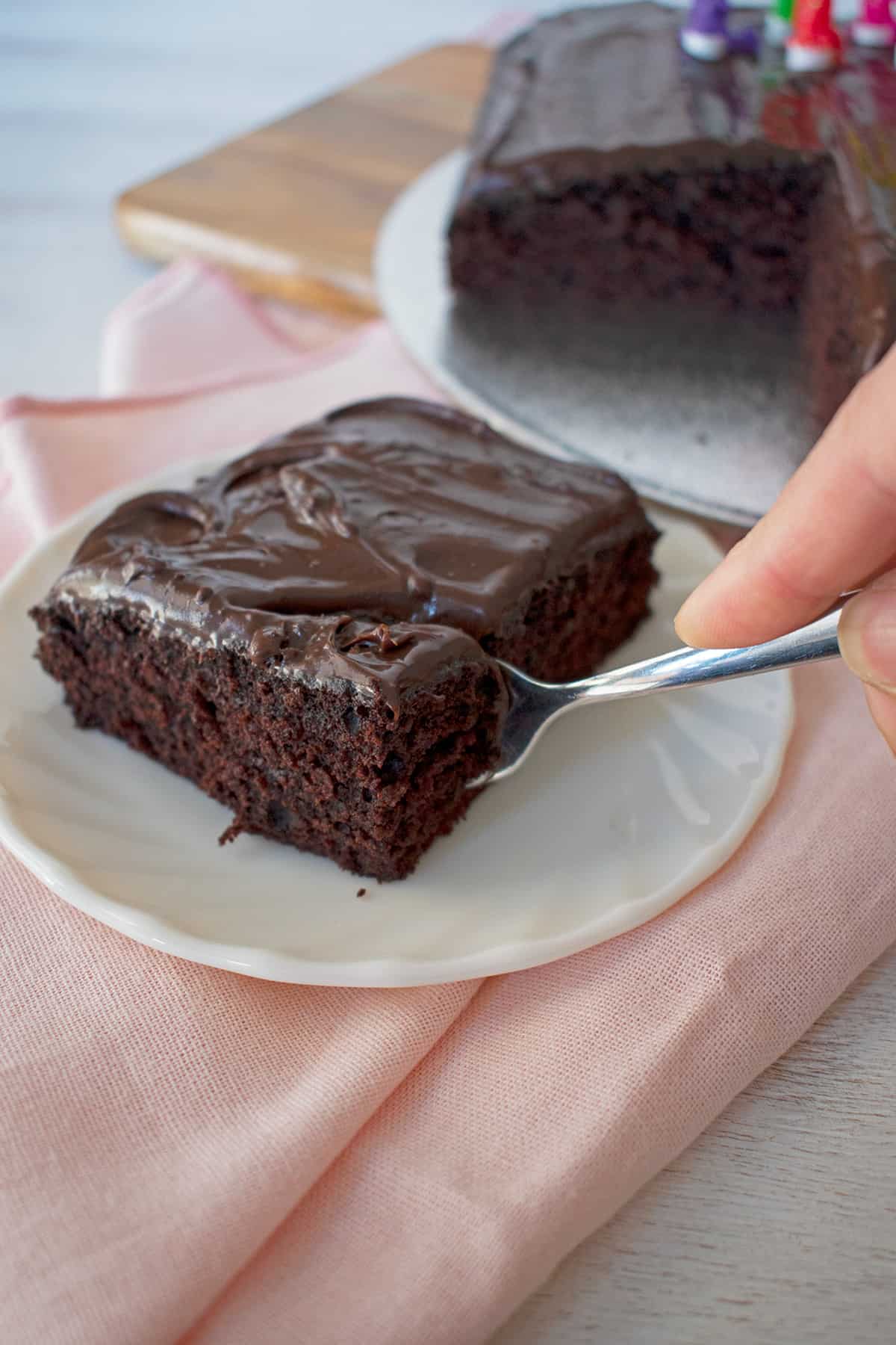 porción pastel de chocolate en un plato blanco, una persona partiendo con un tenedor