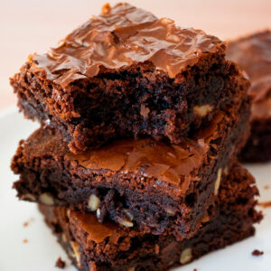 tres brownies caseros uno sobre otro sobre una mesa blanca