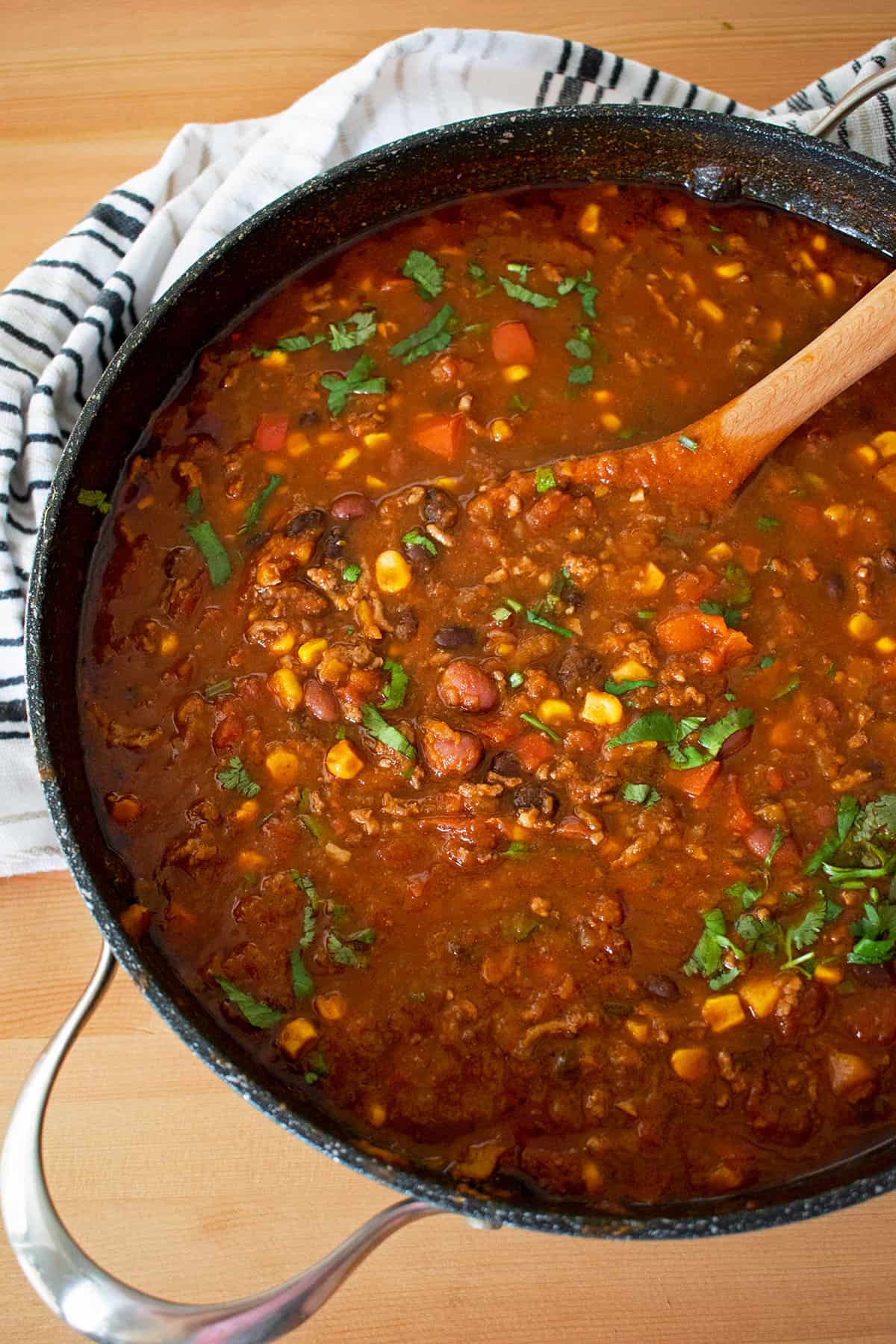 chili con carne casero en una olla grande con una cuchara de madera