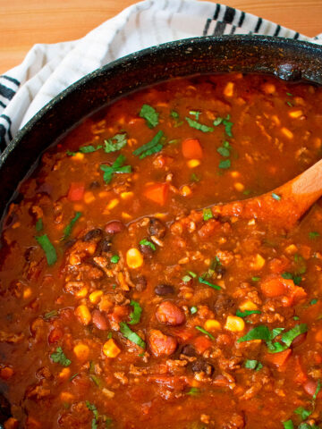 chili con carne en una olla grande con una cuchara de madera