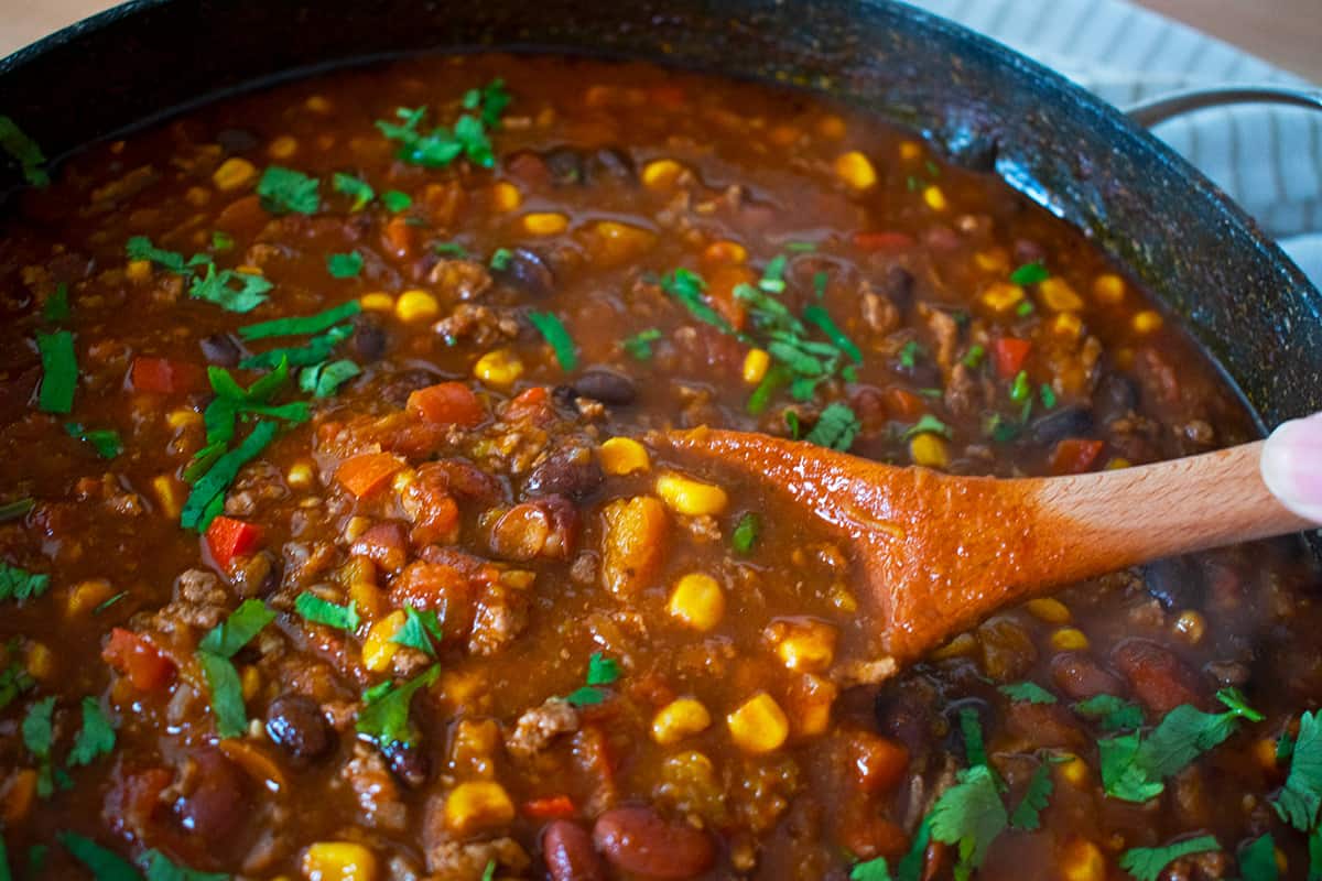 chilli con carne servido en un sartén con una cuchara de madera