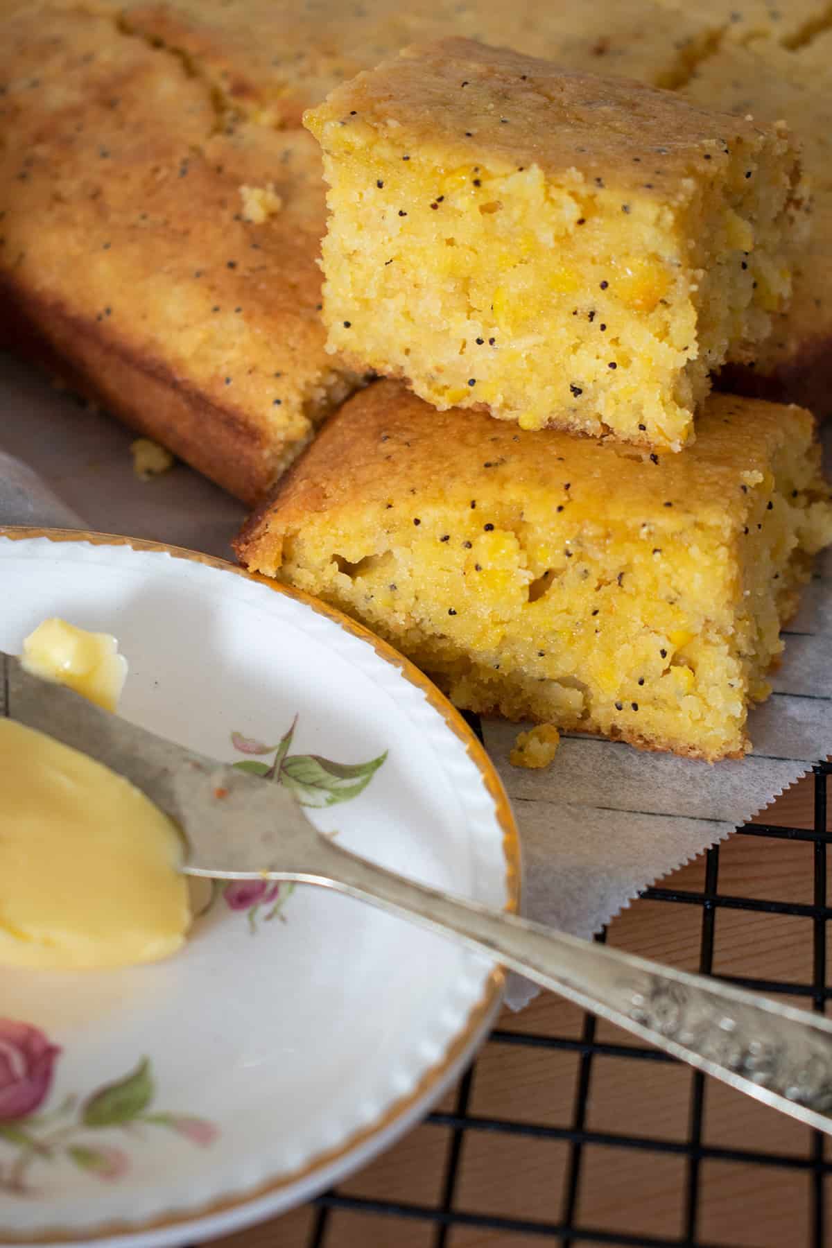 porciones de cornbread sobre una rejilla acompañado de mantequilla en un pequeño plato con flores.