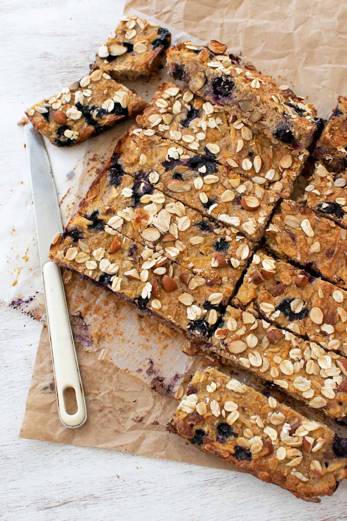 barritas de avena y almendras cortadas sobre un papel pergamino acompañadas de un cuchillo.