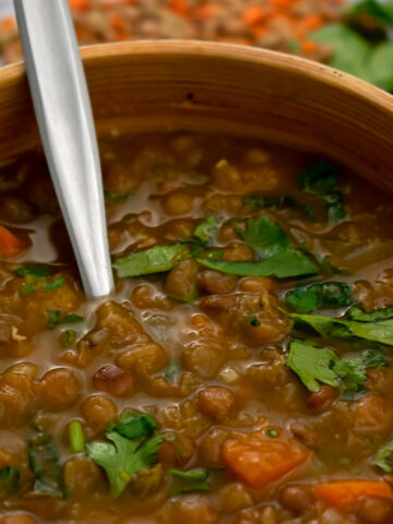 sopa de lentejas servida en un bol con una cuchara platead