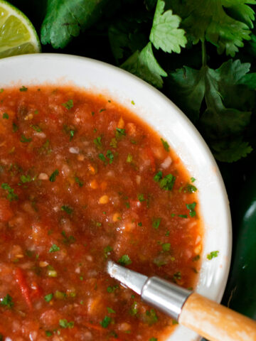 salsa fresca servida en un plato blanco con una cuchara de madera