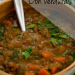 sopa de lentejas servida en un bol con una cuchara plateada