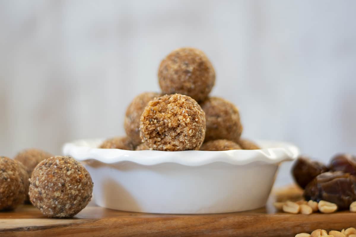 bolitas de dátiles y maní en un bol blanco sobre una mesa de madera