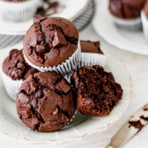 muffins de chocolate servidos en un plato redondo sobre una mesa blanca.