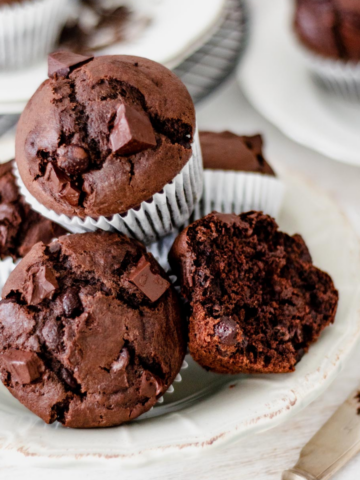 muffins de chocolate servidos en un plato redondo sobre una mesa blanca.