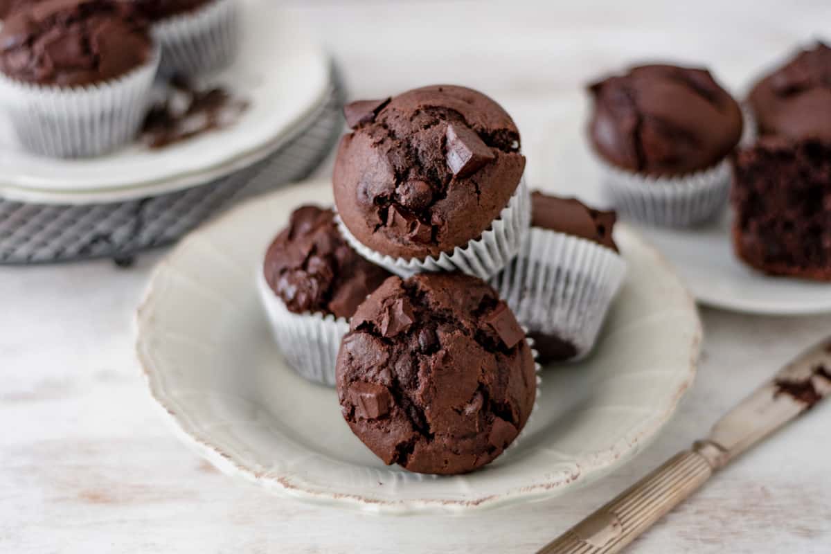 muffins de chocolate esponjosos servidos en un plato redondo sobre una mesa blanca.