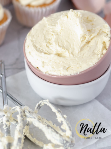 una taza de crema de mantequilla con cupcakes de vanilla en la parte de atrás