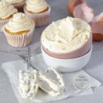 una taza de crema de mantequilla con cupcakes de vanilla en la parte de atrás
