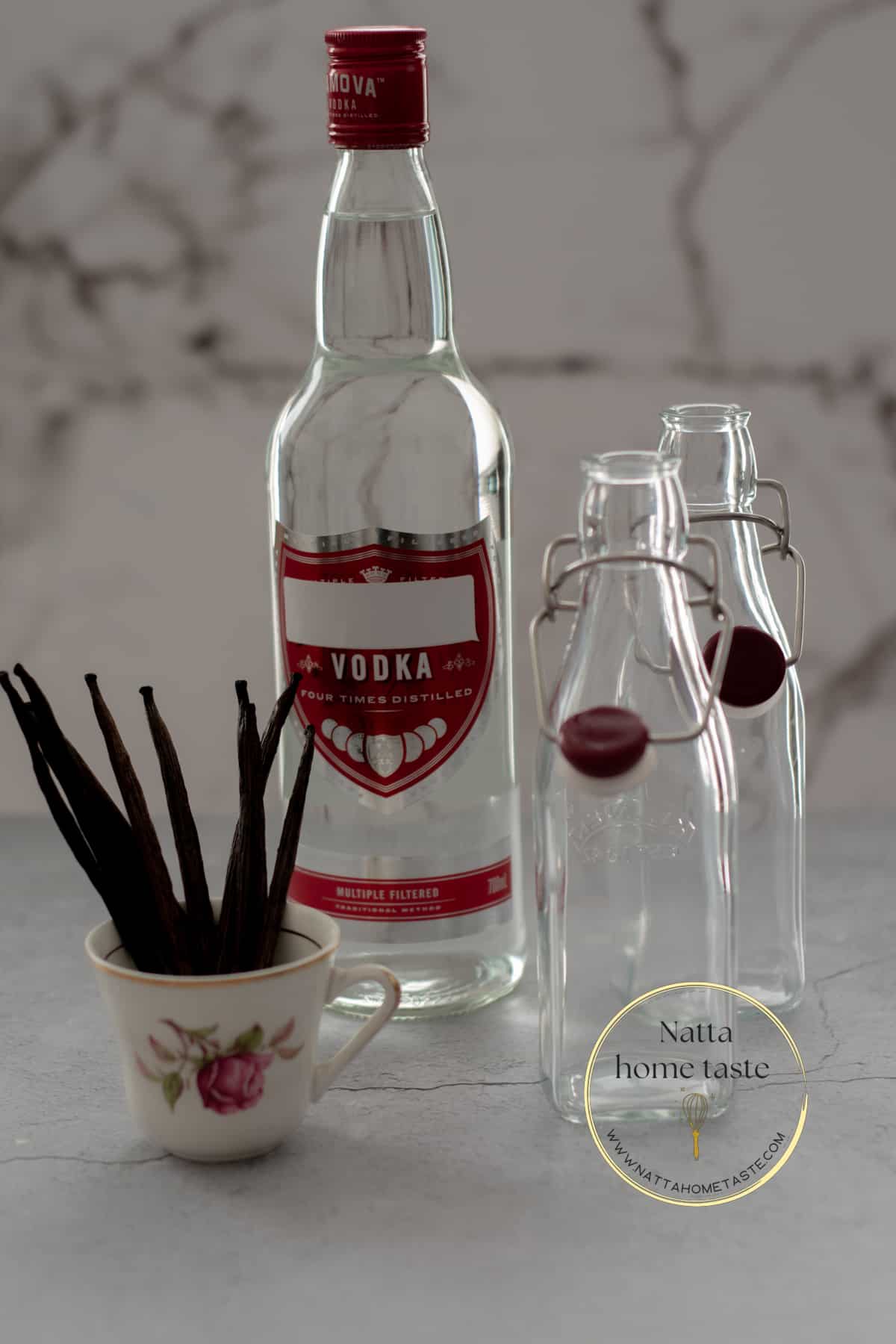 Una botella de vodka, dos botellas de vidrio vacías y vainas de vainilla en un pequeño pocillo.