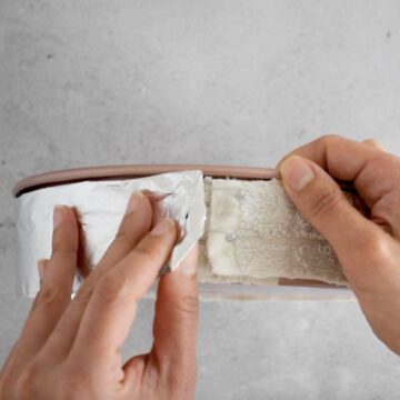 envolviendo papel de aluminio alrededor de un molde redondo para cubrir banda casera para hornear húmeda.