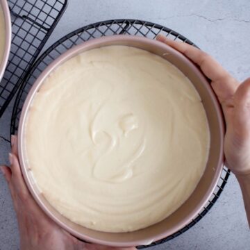 molde redondo rosado con masa de pastel de vainilla listo para llevar al horno.