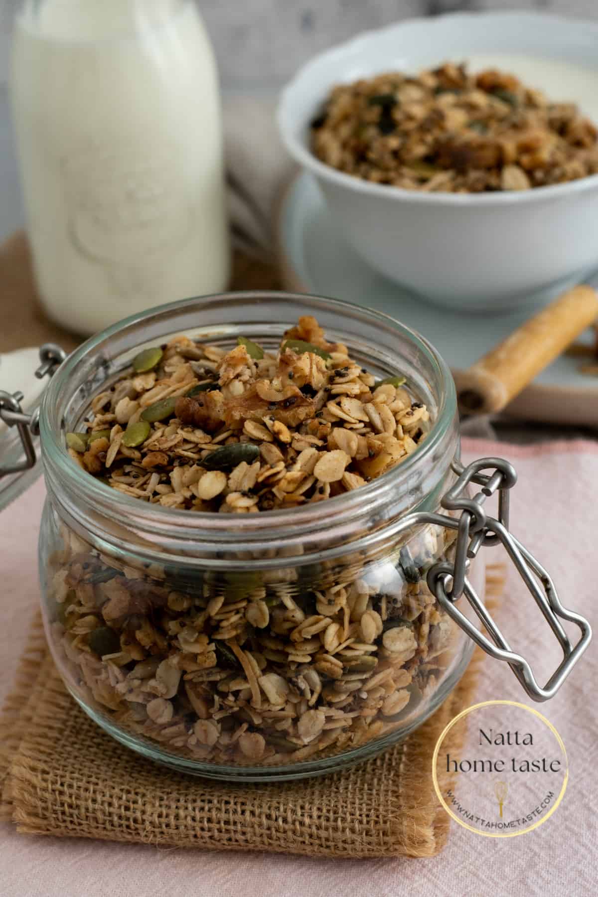 Granola casera en un frasco redondo de vidrio con la tapa abierta. una botella de leche en la parte de atrás.