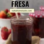 frasco de vidrio con mermelada de fresa casera y una cuchara dentro del frasco. Fresas frescas en la parte de atrás.