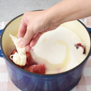 olla grande con fresas, azúcar, limón y semillas de limón envueltas en un pedazo de tela.