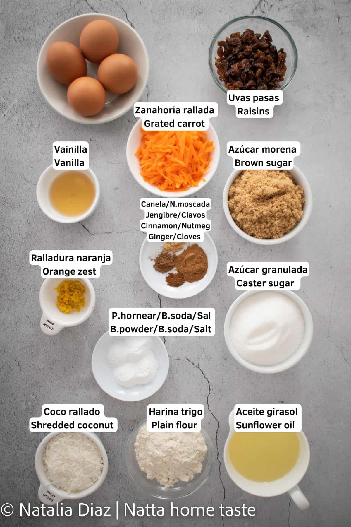 Ingredientes para preparar un torta de zanahoria, todos están servidos en contenedores pequeños. Huevos, uvas pasas, zanahoria rallada, extracto de vainilla, azúcar morena y granulada, harina de trigo, coco rallado, aceite de girasol.