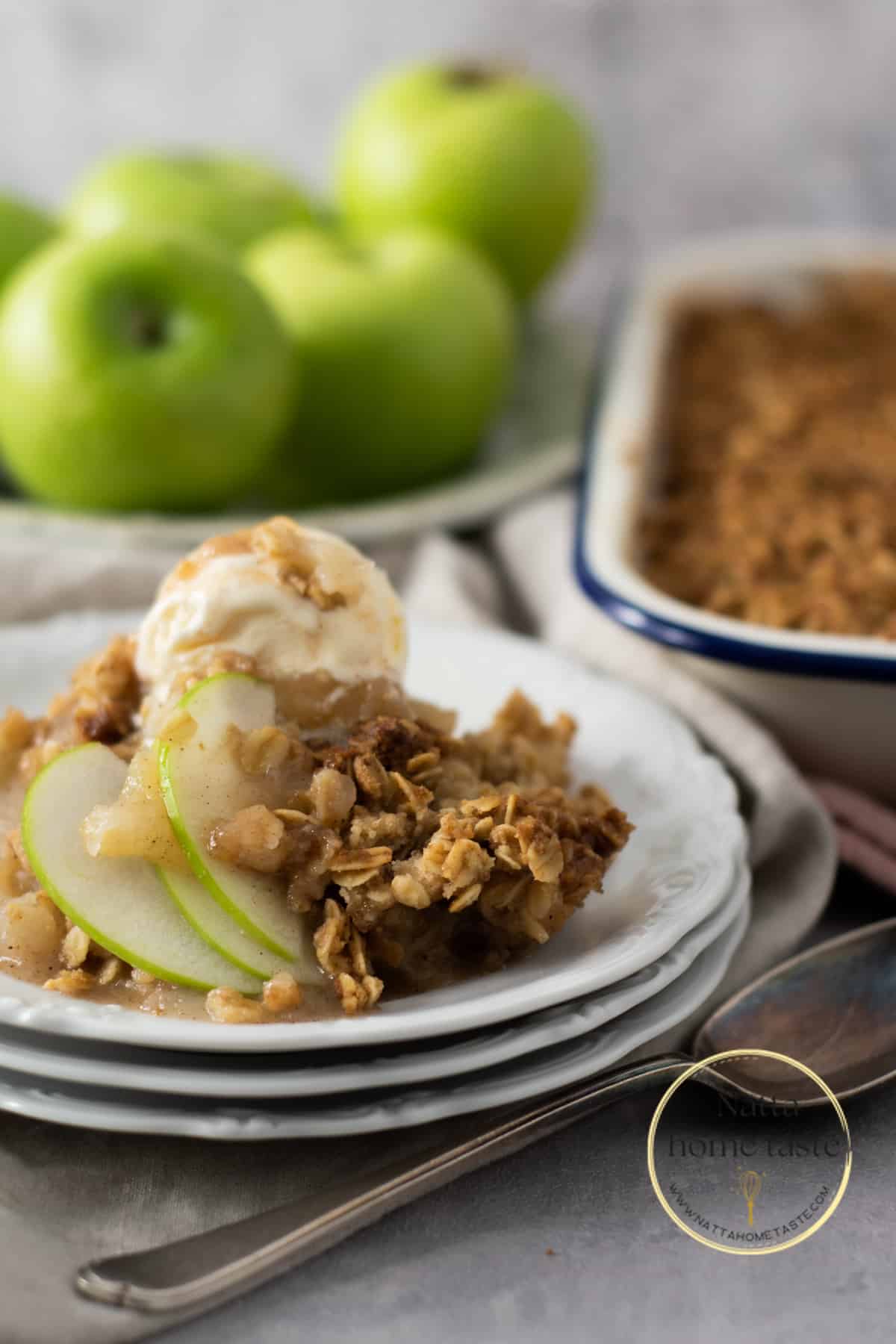 crumble de manzana servido en un plato de blanco con una bola de helado de vainilla.